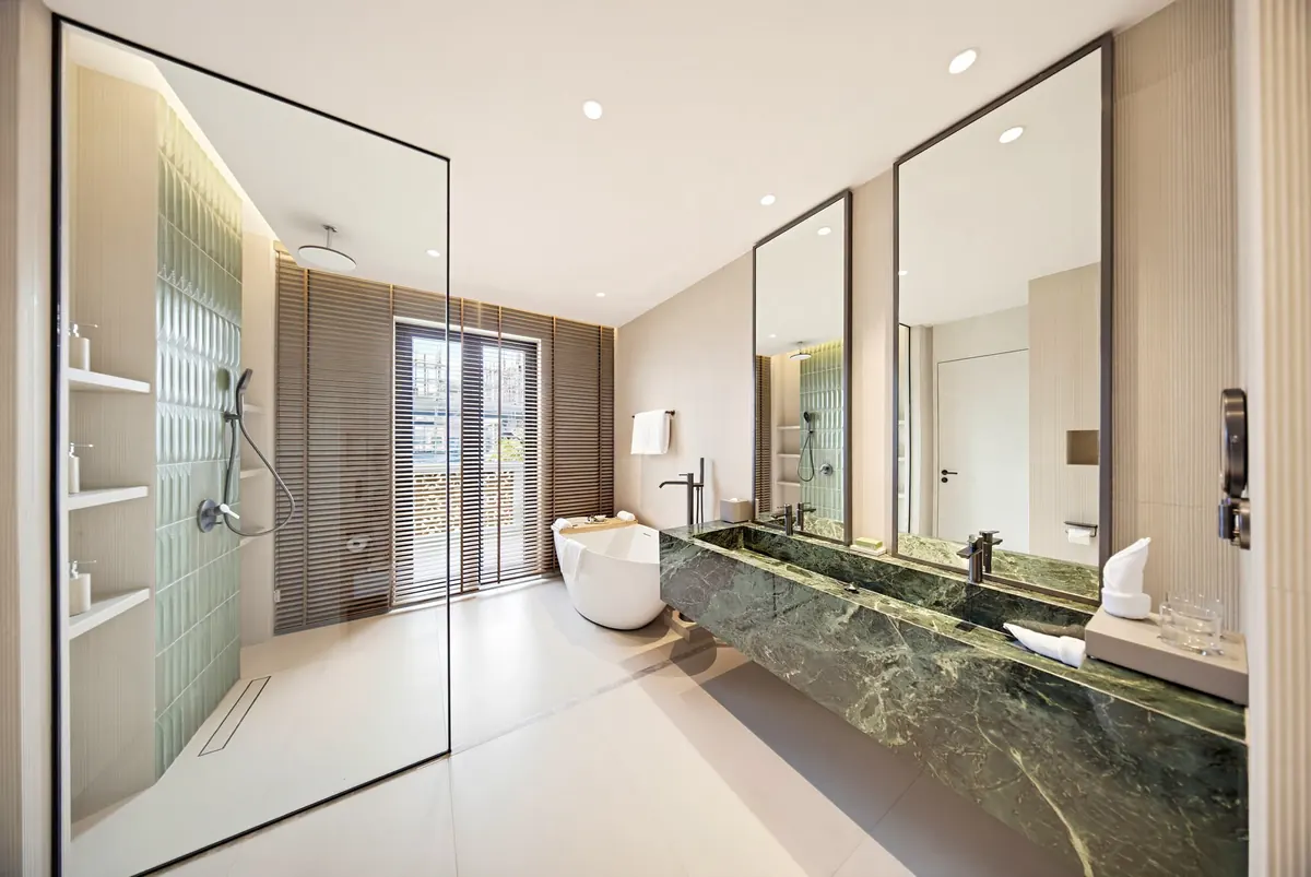 Phòng tắm với lavabo đá xanh bồn tắm nằm và vách kính